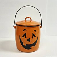 Front view of the vintage Halloween pail showing the orange enamel and black Jack-o-Lantern face with the metal handle in upright position.