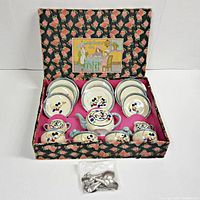 Full view of vintage Mickey Mouse child's tea set in original floral box, showing teapot, sugar bowl, creamer, cups, saucers, plates, and small spoons.