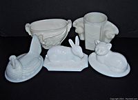 Front view of all five milk glass animal-themed items arranged in one image showing cat, bunny, hen tops, and swan and double horsehead vases.