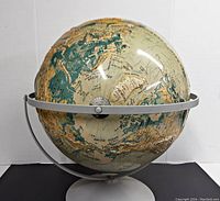 Front view of the vintage Nystrom globe showing the Arctic Ocean and surrounding regions with a metal base.