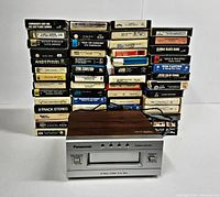 Front view of Panasonic 8-track player and stacked 8-track tapes behind it
