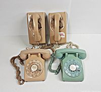 Four vintage rotary dial telephones arranged together: two beige wall-mount models at the back and two desk/table models (beige and green) in front.