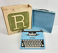 Royal Mariner blue portable typewriter open, with cover behind it and original cardboard box to the side.