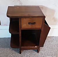 Front and side view of vintage wood smoking stand showing drawer, side magazine rack shelves, and overall shape