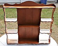 Front view of vintage wooden wall shelf showing overall structure, wood tone, curved scalloped edges, and shelves