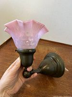 Front side view of the wall sconce showing the opalescent cranberry glass shade with fluted edges and the dark metal mounting base.