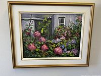 Framed colorful impressionist floral oil painting showing detailed flowers and gray building.