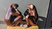 Pair of red glazed ceramic frog bookends sitting side by side, showing glossy mottled brown and red finish with white painted accents on the hands, feet, and faces.