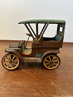 Side view showing stamped lithograph details and structure of the tin toy car