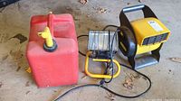 Overview photo of red plastic 5-gallon gas can, yellow portable shop light with bent cage, and yellow Stanley blower/fan.