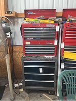 Wide view showing black chest beneath red chests and tools inside drawers