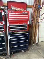 Full front view of the red top chest stacked on the blue bottom cabinet against workshop wall