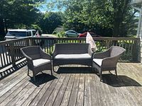 Wide angle showing the full outdoor furniture set on a wooden deck: one bench, two chairs, and an umbrella folded beside the bench.