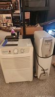 Photo showing Comfort-Aire dehumidifier model BHD-301 and DeLonghi space heater side by side on carpet floor.