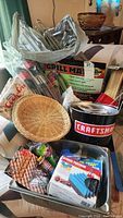 Photo of assorted grilling items including kabob baskets, wooden skewers, wicker basket, grill mats, Craftsman ice bucket, and packaging of various grilling tools.