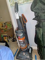 Full view of the upright Hoover vacuum cleaner with hose and attachments in a room.