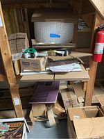 Photo showing multiple shelves holding shipping supplies including bubble wrap, cardboard boxes, packing tape dispenser, and rolls of tape.