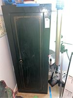 Front view of green metal Stack-On storage cabinet showing door with gold decorative stripes.