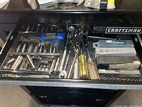 First drawer containing socket wrenches, bits, and screwdriver with blue handle