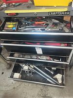 View of the four open drawers of the Craftsman tool chest showing various hand and specialty tools inside, including wrenches, pliers, and sockets.