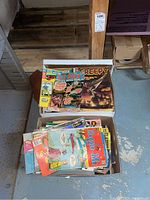 Two cardboard boxes filled with vintage comic books showing titles like Sgt. Rock, Creepy, and others, placed on a basement floor.