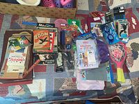 Top view of the lot showing board games, card games, glow figures, swim goggles, and toy racquets.