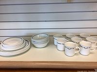 Corelle cups, bowls, and stacked plates displayed on a shelf.