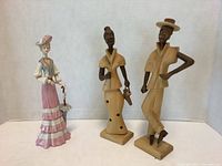 Photo showing front view of the ceramic lady figure alongside two carved wood figures.