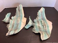 Two fish-shaped clay decor pieces shown from above, placed side by side on a black surface, highlighting size and coloration.