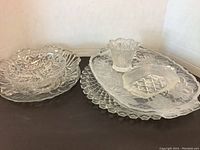 Glass serve ware lot featuring large platters and a small segmented candy dish on a white background