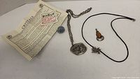 Four necklaces and a blue crystal with informational leaflet laid out flat on a white surface.