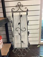 Front view of metal wine rack with scroll design and grape cluster decorations