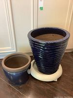 Wide view showing both pots side by side, highlighting size difference and wheeled base for the larger pot.