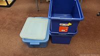 Shows three translucent blue file storage boxes stacked with lids and one larger solid blue storage bin.