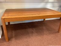 Full view of rectangular teak coffee table on carpet showing overall condition and surface wear.