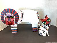 Two wooden cat figurines painted with colorful tribal-style faces and patterns shown together