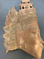 Front view of the wood carved face showing detailed headdress and facial features.