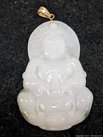 Front facing detailed view of the white jadeite pendant with a 14K yellow gold bail on top against a black background.