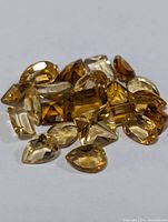 Group of faceted citrine gemstones in multiple shapes and varying yellow to amber colors.