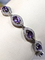 Close-up image of sterling silver bracelet showing oval purple amethyst stones surrounded by clear cubic zirconia.