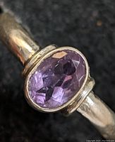 Close-up of oval faceted purple amethyst gemstone set in a sterling silver ring band.