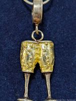 Front view of the silver pendant shaped as shorts over legs pendant on chain