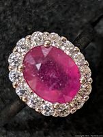 Close-up photo of the sterling silver ring showcasing the oval ruby center stone surrounded by clear cubic zirconia stones.