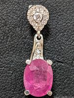 Front view of the sterling silver pendant showing the oval ruby gemstone and CZ stones on the teardrop top and triangular section.
