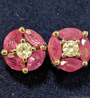 Close-up of front of ruby and diamond sterling silver earrings showing ruby marquise cut stones surrounding central clear stones.