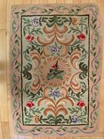 Full view of the rectangular hand hooked wool rug showing colorful floral and foliage pattern with border.