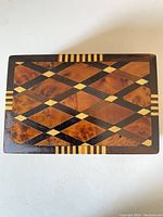Top view showing the intricate inlaid geometric pattern with diamonds and stripes in multiple wood colors and burled maple background.