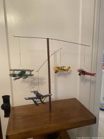 Full view of the balancing airplane mobile showing four suspended old style planes on wooden base.