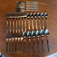 Full overview of all cutlery pieces laid out on a wooden surface, grouped by type.