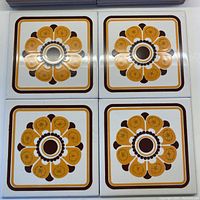 Four ceramic tiles arranged in a square showing the mid-century floral pattern with a central hole for a fixture.